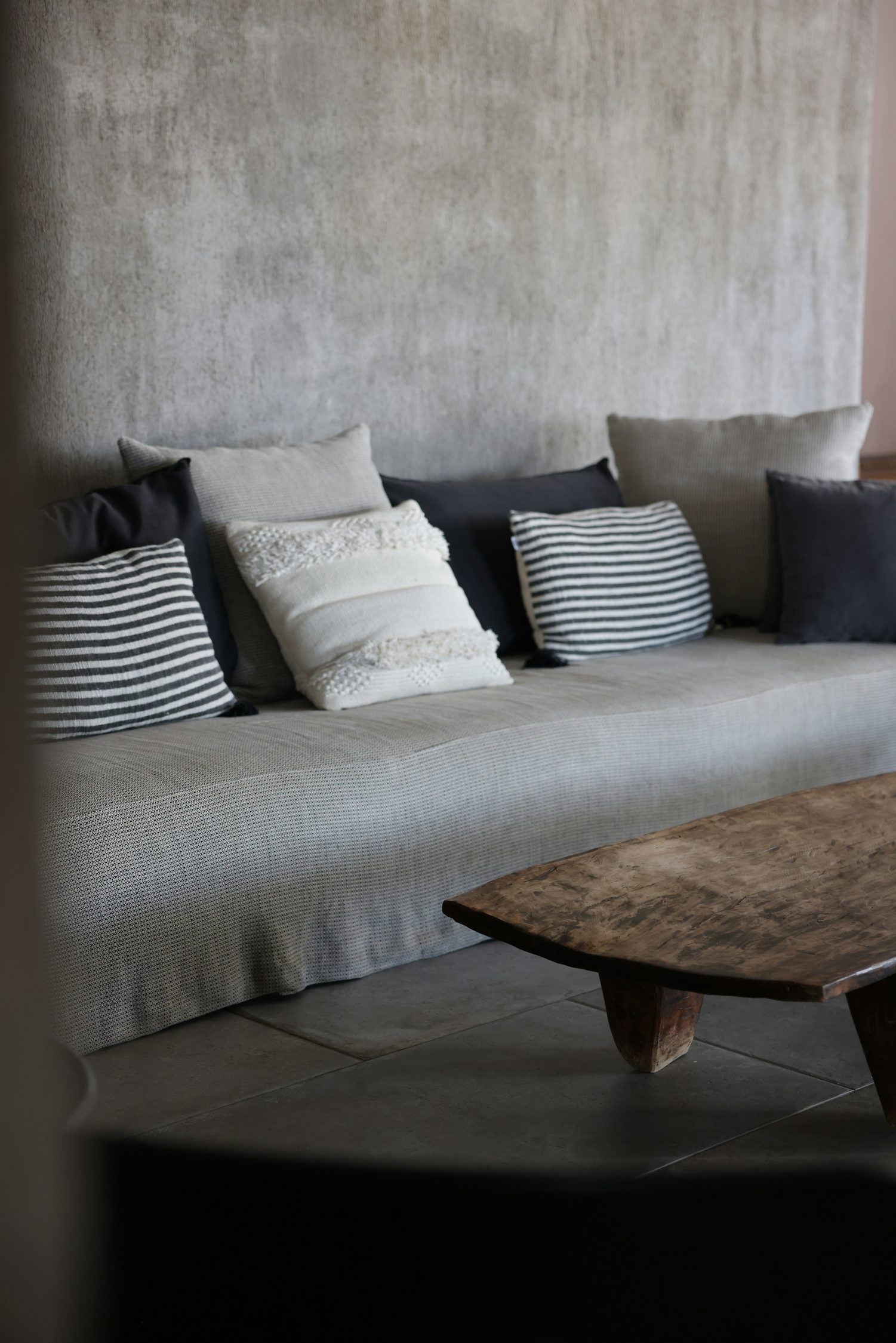 The Haven Coffee Table: a low timber table in front of a grey sofa with striped cushions