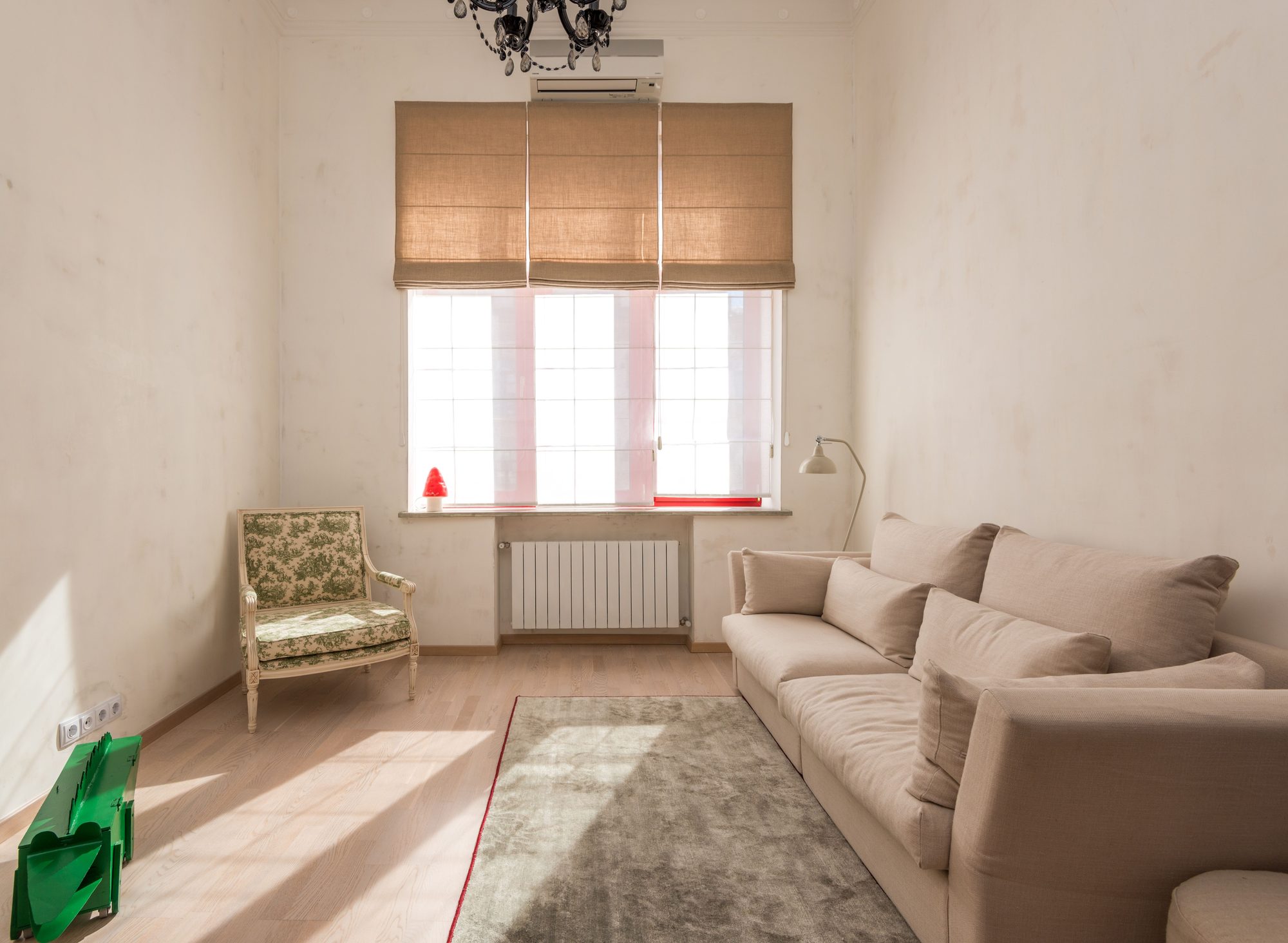 A sunlit living room with a beige sofa, a soft rug and a woven roman blind